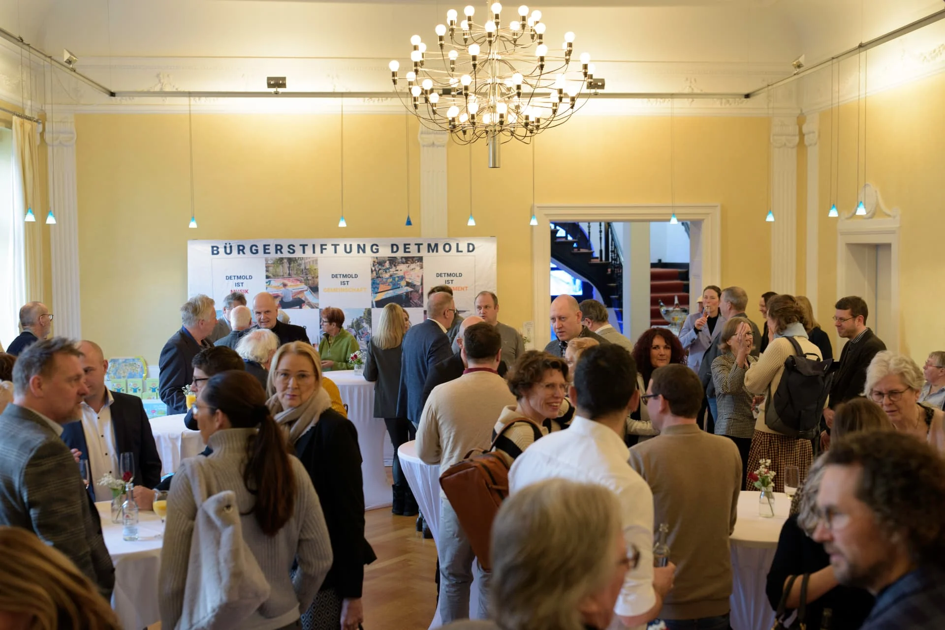 Gäste des Neujahrsempfangs im Saal der Loge vor dem Rollup der Bürgerstiftung Detmold.