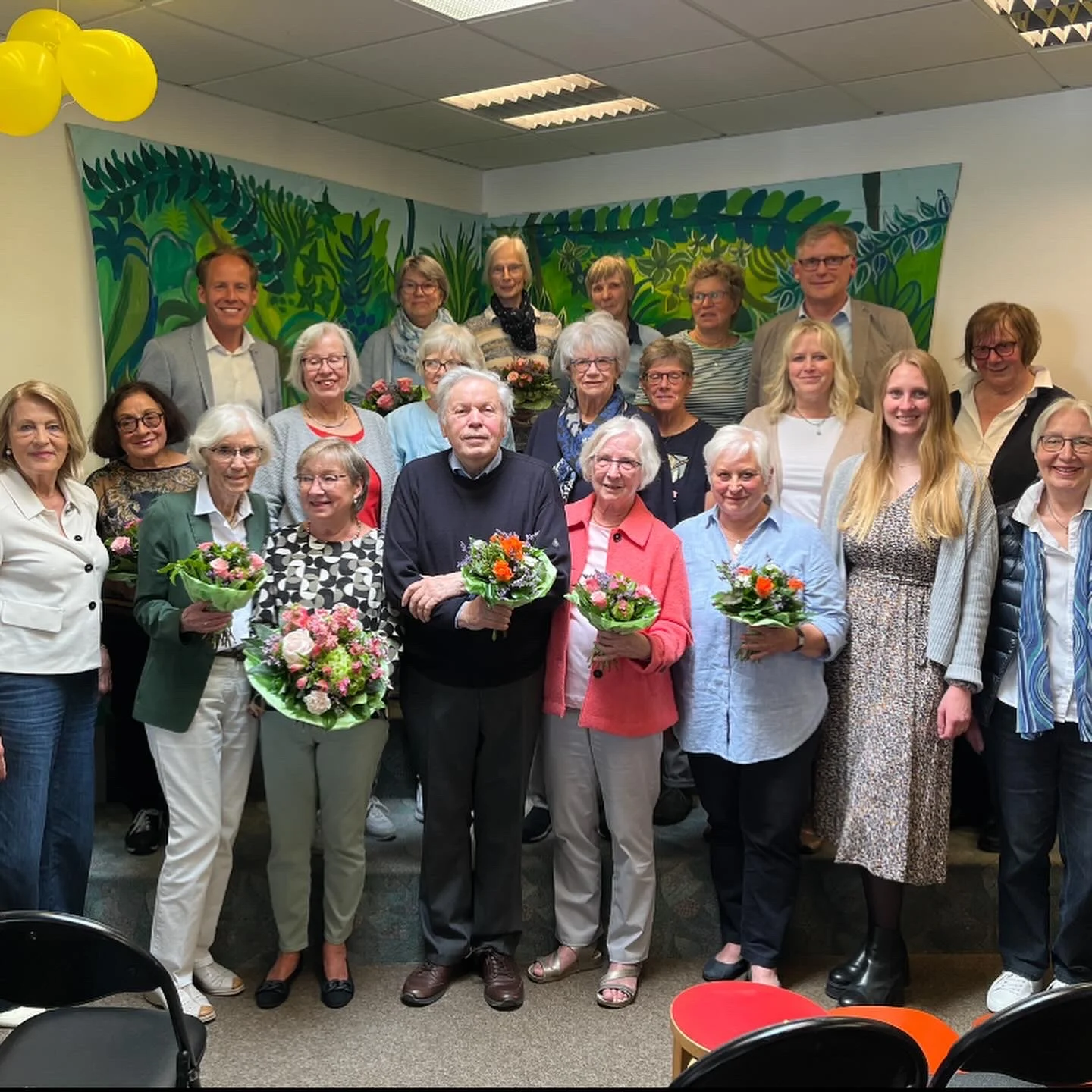 Gruppenfoto des ehrenamtlichen Teams der Bücherei Hiddesen mit Blumensträußen bei der Jubiläumsfeier