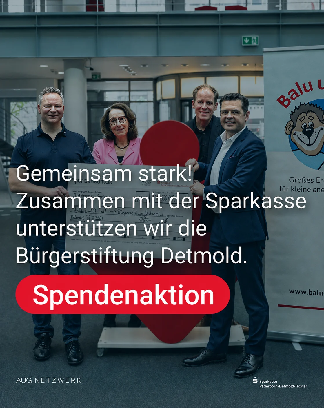 Vier Personen halten einen großen Spendenscheck der Sparkasse für das Projekt „Balu und Du“ der Bürgerstiftung Detmold