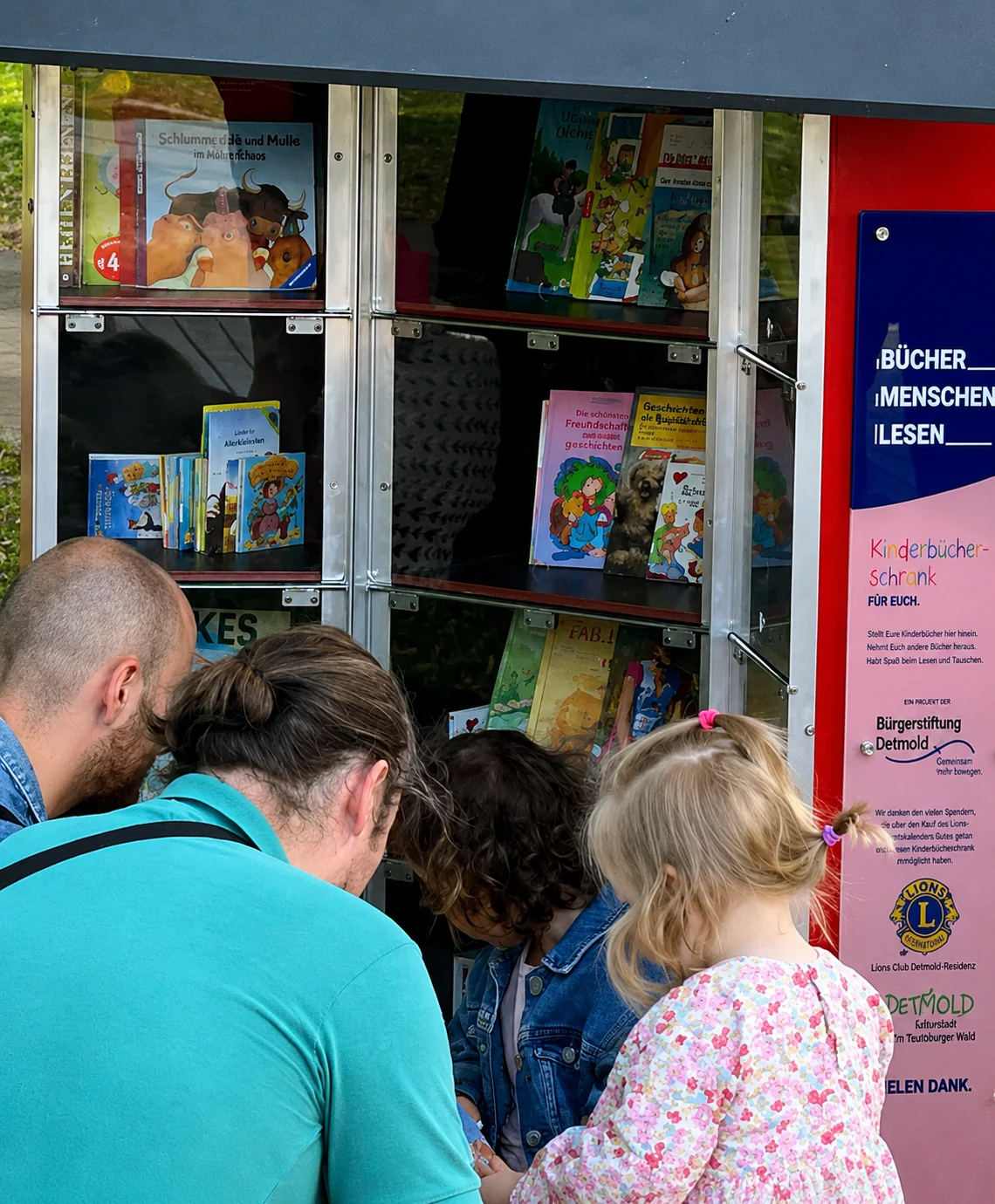 Familie entdeckt gemeinsam die BĂĽcher im KinderbĂĽcherschrank