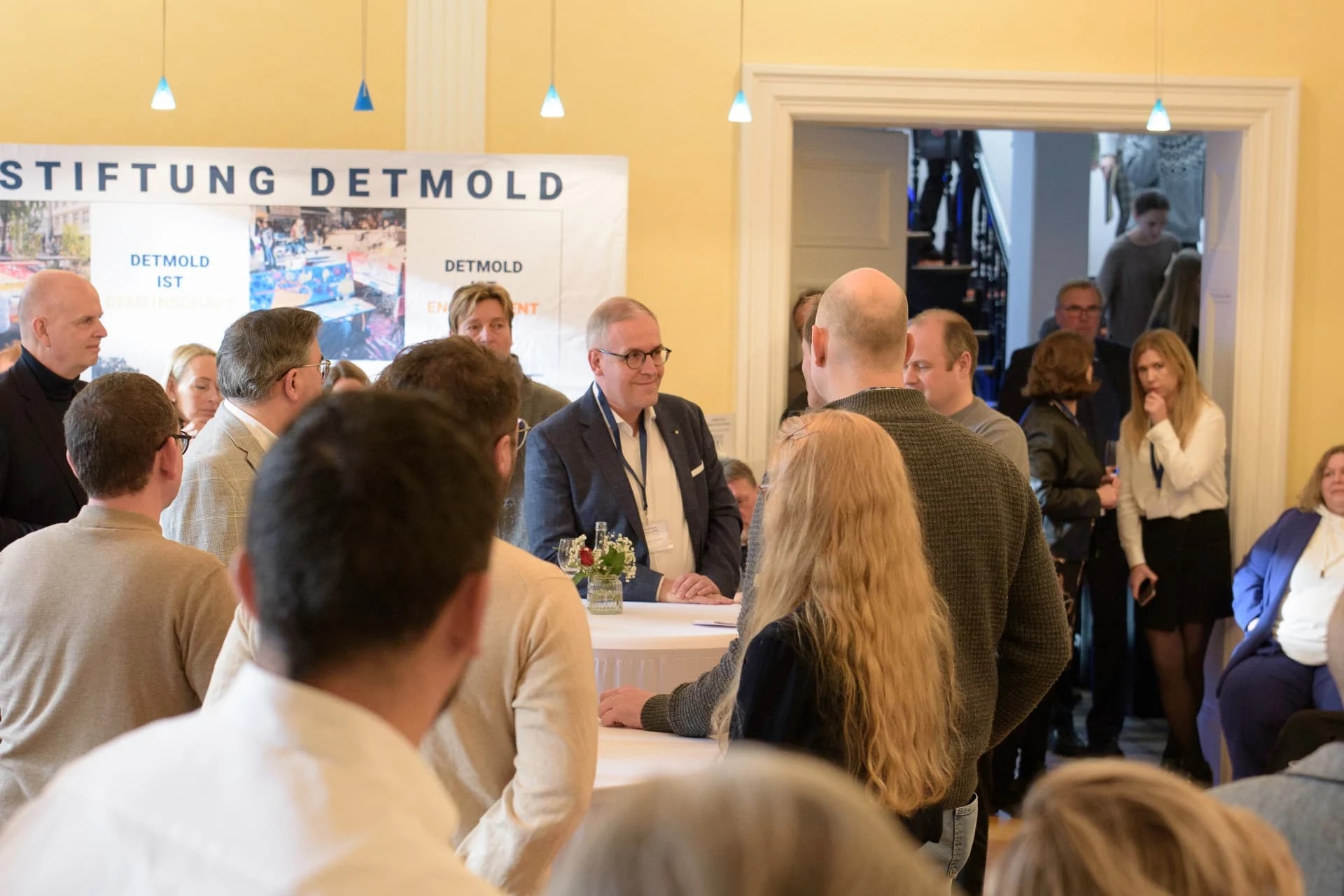 Gäste im Gespräch vor der Präsentationswand „Bürgerstiftung Detmold“.