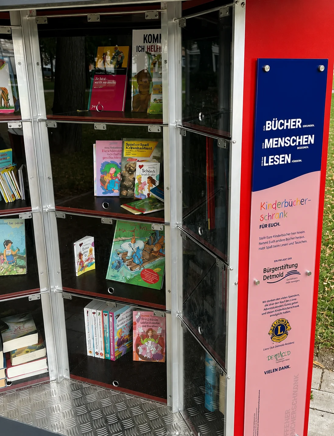 KinderbĂĽcherschrank an der Christuskirche in Detmold, gefĂĽllt mit bunten KinderbĂĽchern